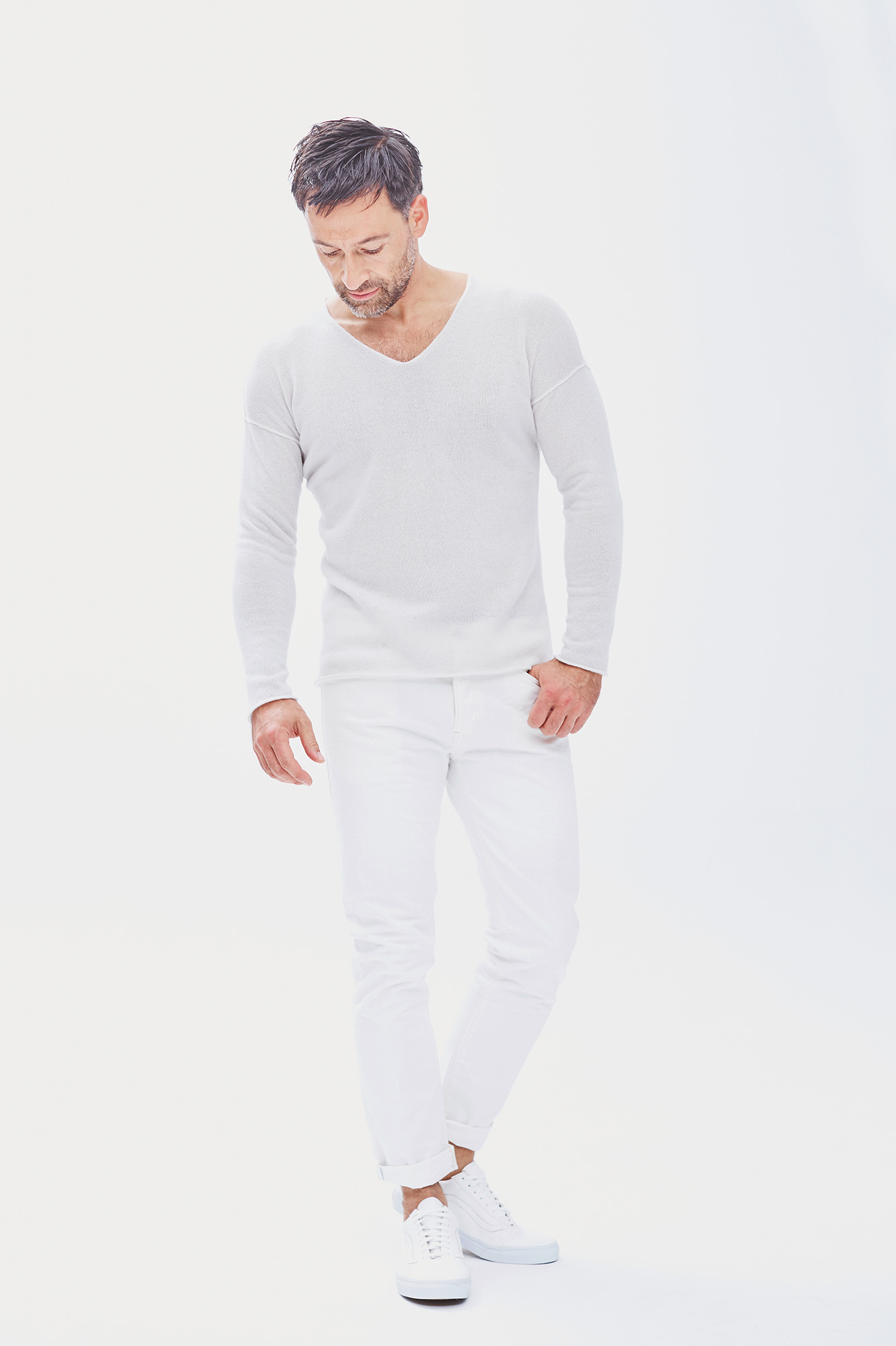 Man in a white cashmere V-neck and white jeans for Villa Gaia