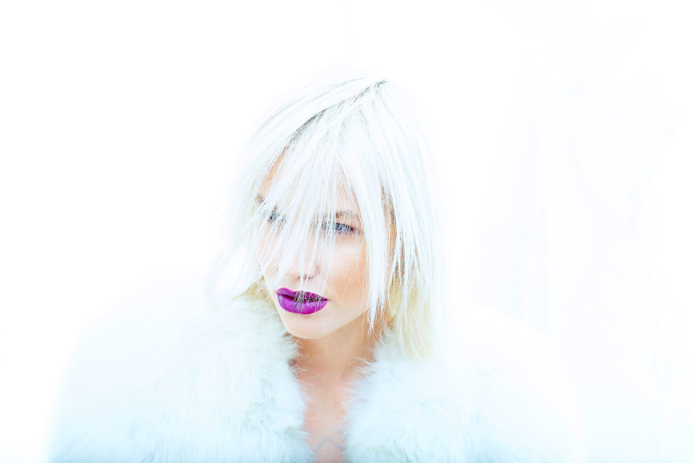 High-key beauty portrait: white hair falling across the face, magenta lips, white fur