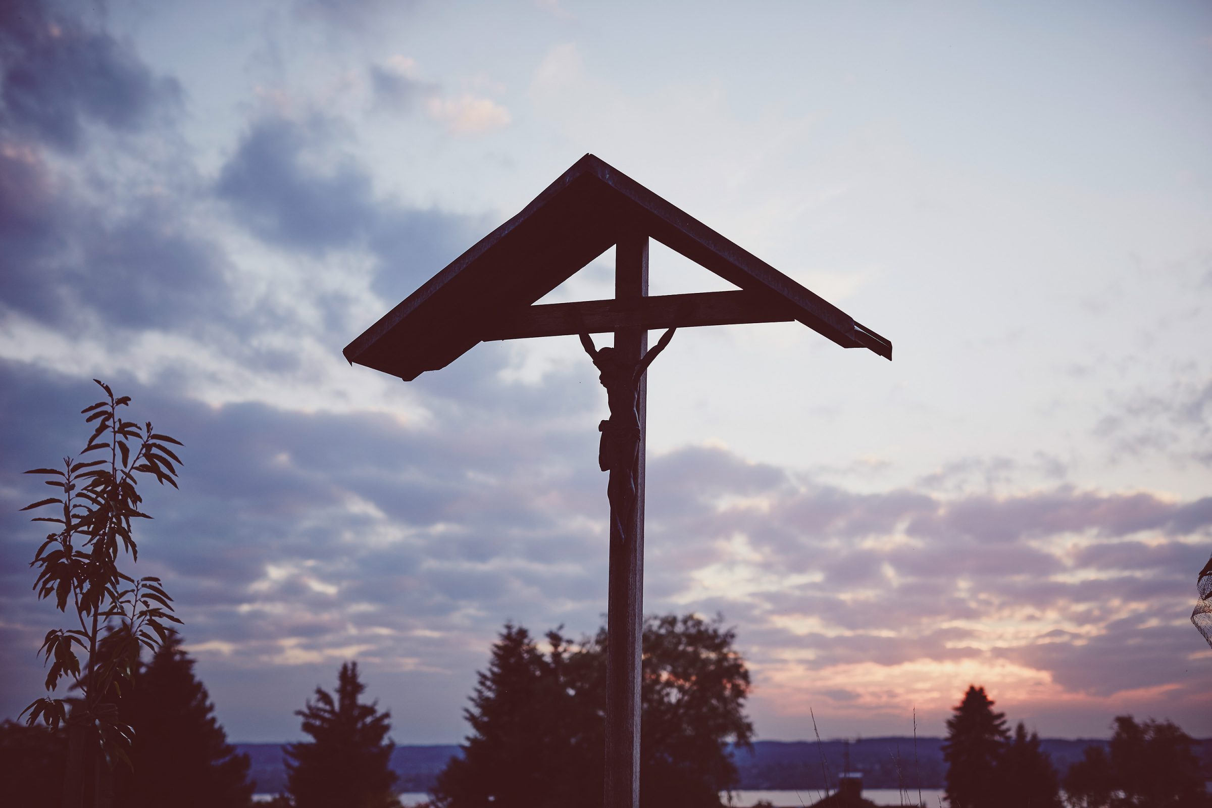 Wayside crucifix in silhouette against an evening sky above Lake Chiemsee