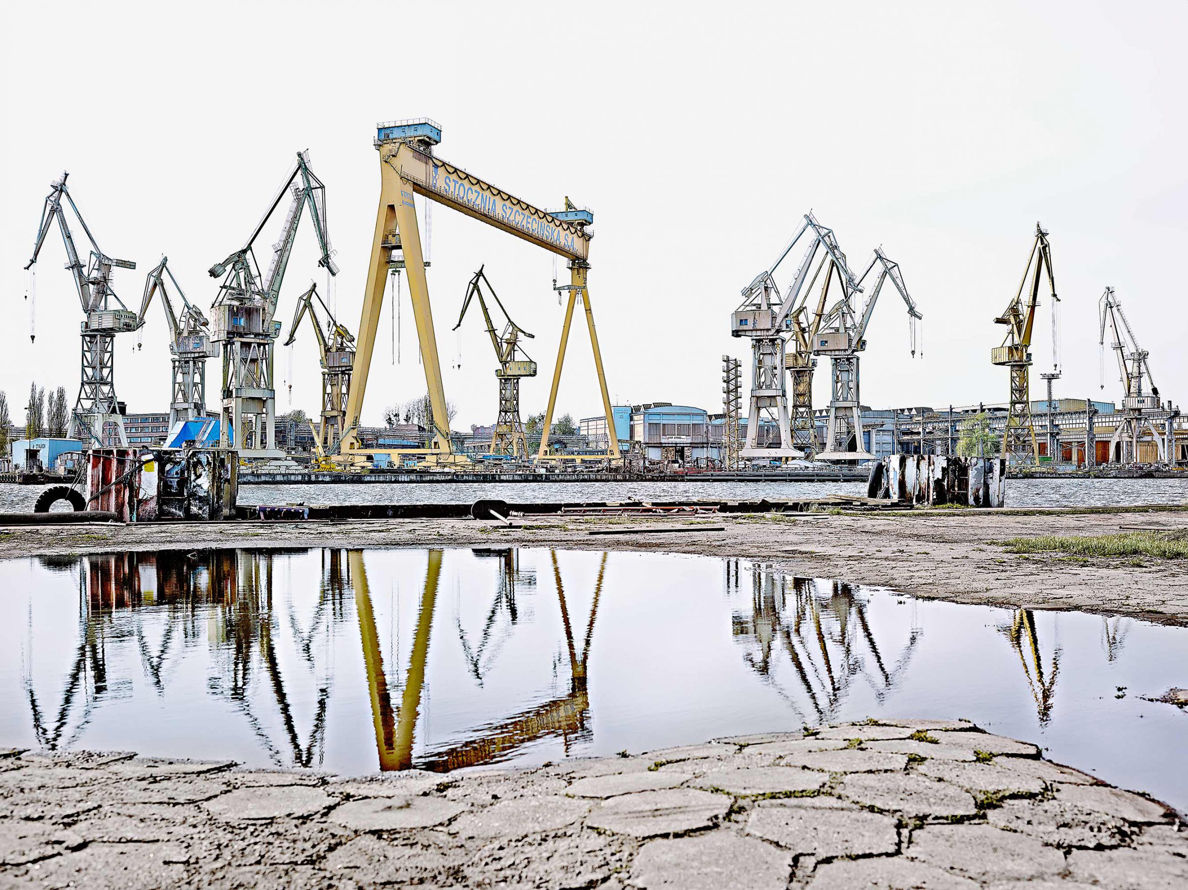 Cranes of the Szczecin shipyard reflected in a puddle, Poland